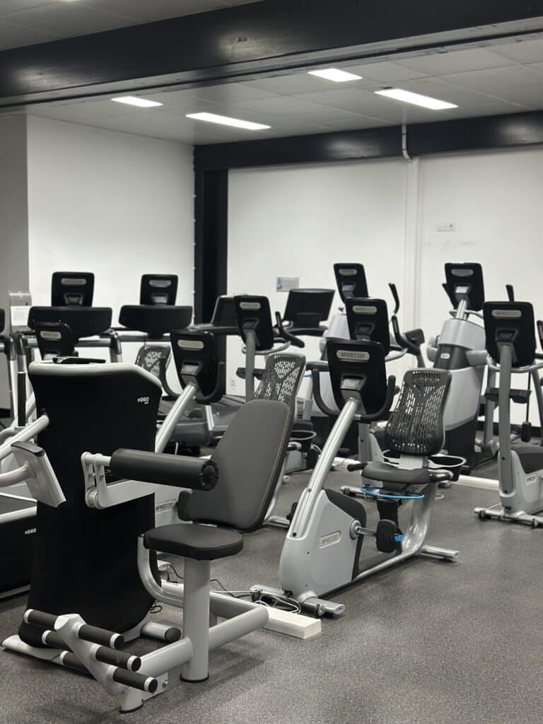 Équipements cardio Precor dans une salle de sport moderne Salle de sport avec vélos d'exercice et tapis Precor alignés dans un espace lumineux.