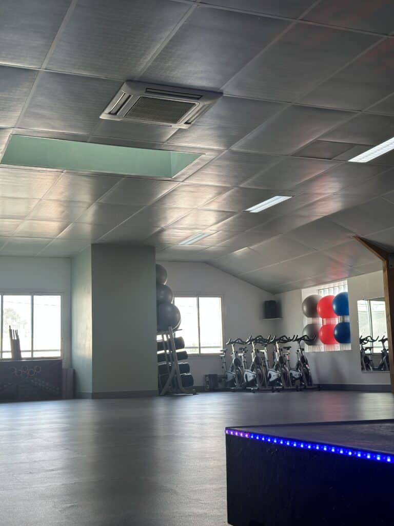 Salle de Fitness Moderne : Vélos de Spinning et Matériel Salle de fitness avec vélos de spinning, ballons de gym et plafond moderne.